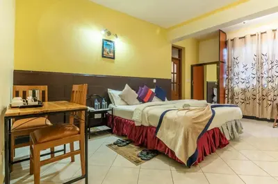 a bedroom with a bed and a table and a desk at Crest Safari Lodge Bed and Breakfast in Arusha