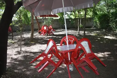 a group of red tables and chairs under an umbrella at Rainbow Executive Lodge in Boma la Ngombe