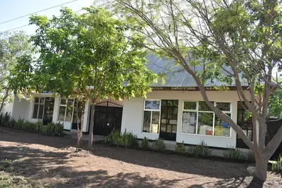 a white building with trees in front of it at Rainbow Executive Lodge in Boma la Ngombe
