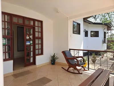 a living room with a rocking chair on a porch at Rainbow Executive Lodge in Boma la Ngombe