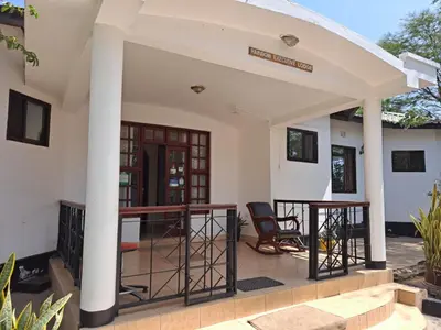 a patio with a table and chairs in a house at Rainbow Executive Lodge in Boma la Ngombe