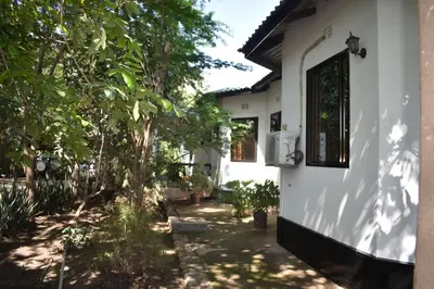a side view of a white house with trees at Rainbow Executive Lodge in Boma la Ngombe