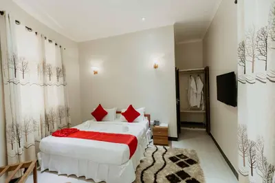 a bedroom with two white beds and red pillows at Panama Garden Resort in Moshi