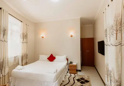 a bedroom with two white beds and a television at Panama Garden Resort in Moshi
