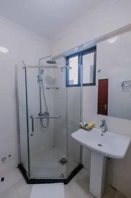 a bathroom with a glass shower and a sink at Panama Garden Resort in Moshi