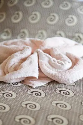 a pink towel laying on top of a bed at More Than A Drop in Moshi