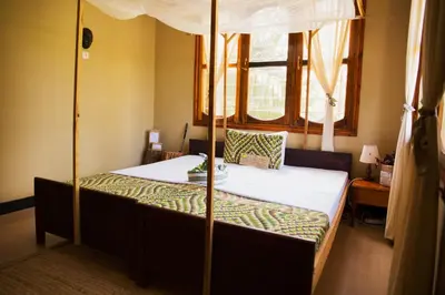 a bedroom with a canopy bed with white sheets at More Than A Drop in Moshi