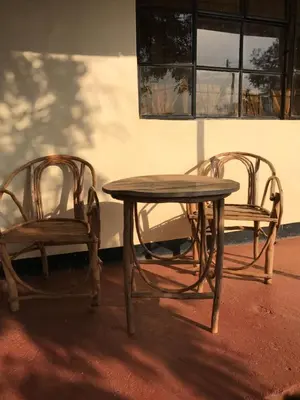 two chairs and a wooden table and a table and chairs at More Than A Drop in Moshi