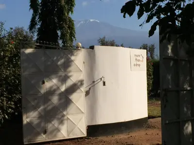 a white door with a gate with a mountain in the background at More Than A Drop in Moshi