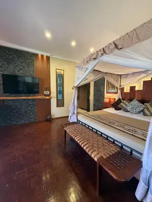 a bedroom with a large bed and a bench at Ameg Lodge Kilimanjaro in Moshi