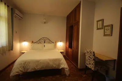 a bedroom with a bed and two tables and a chair at Boulevard Inn Mt Meru in Arusha