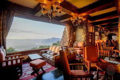 a living room with a couch and a large window at Ngorongoro Serena Safari Lodge in Ngorongoro