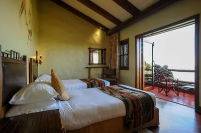 a bedroom with two beds and a large sliding glass door at Ngorongoro Serena Safari Lodge in Ngorongoro