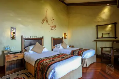 a hotel room with two beds and a mirror at Ngorongoro Serena Safari Lodge in Ngorongoro