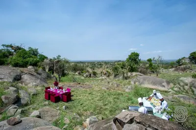 a group of people sitting around a table on some rocks at Mbuzi Mawe Serena Camp in Serengeti