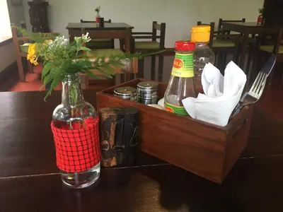 a wooden crate with a bottle and a vase with sauces at Bristol Cottages Kilimanjaro in Moshi