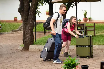 a man and a woman with luggage on a sidewalk at Bristol Cottages Kilimanjaro in Moshi