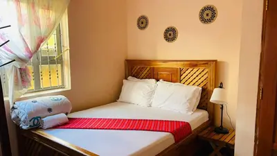 a small bedroom with a bed and a window at Maasai Hostel Tanzania in Arusha