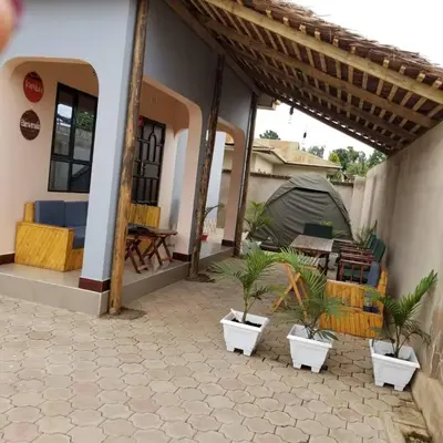 a patio of a house with potted plants and a tent at Maasai Hostel Tanzania in Arusha