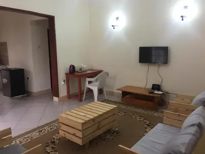 a living room with a couch and a table and a television at Le Parlour in Boma la Ngombe