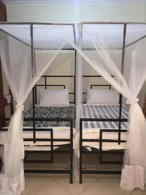 two bunk beds in a room with white curtains at Le Parlour in Boma la Ngombe