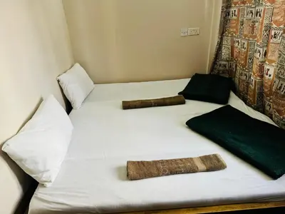 a bed with two pillows on it with two blankets at Arusha Backpackers Hotel in Arusha