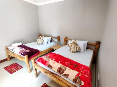 two beds in a room with red and white blankets at Wanyama B&B in Arusha
