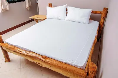 a wooden bed with two pillows on top of it at Wanyama B&B in Arusha