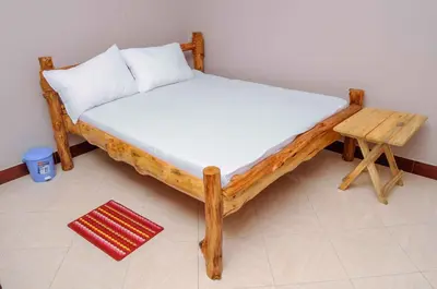a bed with a wooden frame and a table at Wanyama B&B in Arusha