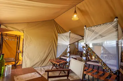 a tent with a table and chairs in it at Gnu Ndutu Camp in Sinoni