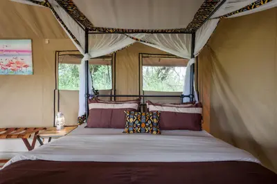 a bedroom with a bed in a tent at Gnu Ndutu Camp in Sinoni