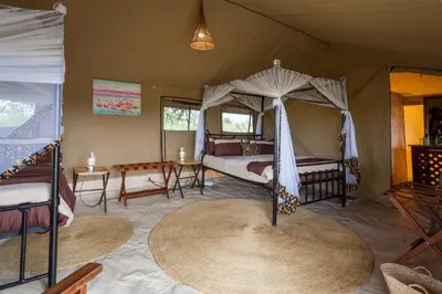 a bedroom with a canopy bed and a table at Gnu Ndutu Camp in Sinoni