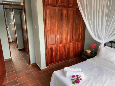 a bedroom with a white bed with a wooden cabinet at Daria Apartment -Burka -3 minutes from Arusha Airport in Arusha