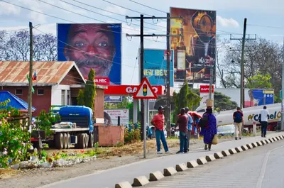 a group of people walking down a street with billboards at Arusha Villa Karamu Coffee Estate in Usa River