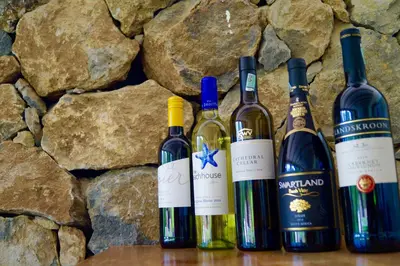 four bottles of wine sitting next to a stone wall at Arusha Villa Karamu Coffee Estate in Usa River