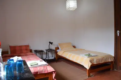 a room with two beds and a table at The Researchers Rest in Arusha