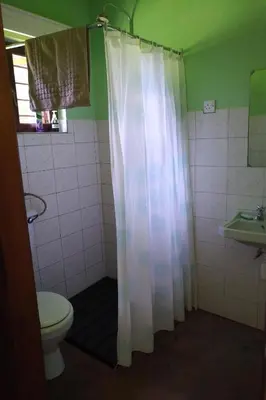 a bathroom with a white shower curtain and a toilet at The Researchers Rest in Arusha
