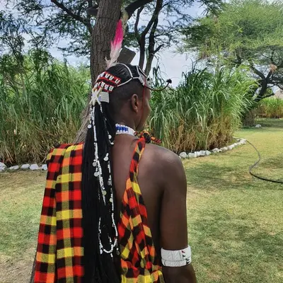 a woman wearing a plaid cape and araid at Lake Natron Maasai giraffe eco Lodge and camping in Mtowabaga