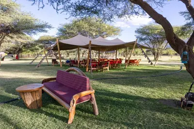 a swing chair and a table in a park at Lake Natron Maasai giraffe eco Lodge and camping in Mtowabaga