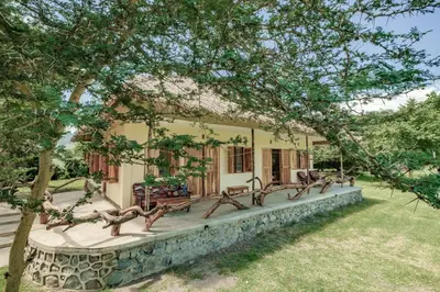 a house with a group of benches in front of it at Lake Natron Maasai giraffe eco Lodge and camping in Mtowabaga