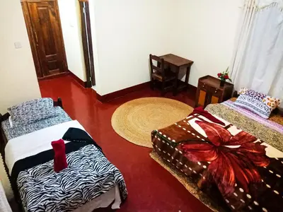 a room with two beds and a table and arero at Shimbwe Meadows Home in Moshi