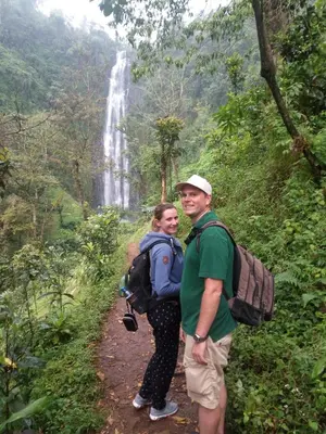 a man and woman standing on a trail in front of a waterfall at Shimbwe Meadows Home in Moshi