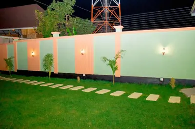 a wall with palm trees in a field of grass at Jaden Hotel & Lounge - Arusha in Arusha