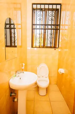 a bathroom with a sink and a toilet and a window at Jaden Hotel & Lounge - Arusha in Arusha