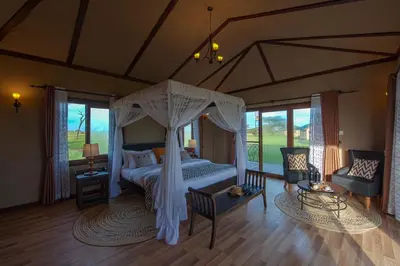 a bedroom with a canopy bed and a living room at Serengeti Sametu Camp in Serengeti National Park