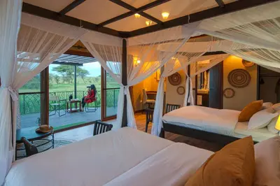 a bedroom with two beds and a balcony at Serengeti Sametu Camp in Serengeti National Park