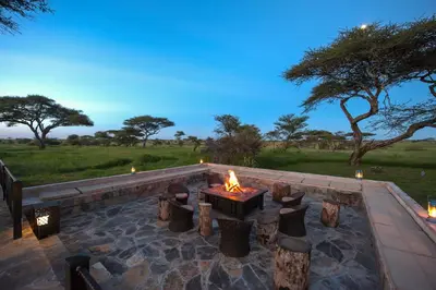 a fire pit with a table and some trees at Serengeti Sametu Camp in Serengeti National Park