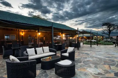 a patio with couches and chairs and a table at Serengeti Sametu Camp in Serengeti National Park