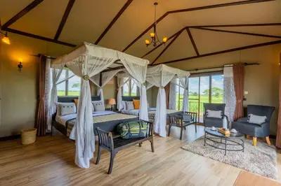 a bedroom with a canopy bed and two chairs at Serengeti Sametu Camp in Serengeti National Park