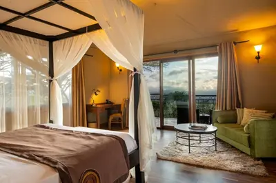 a bedroom with a bed and a couch and a table at Ngorongoro Lion's Paw in Ngorongoro